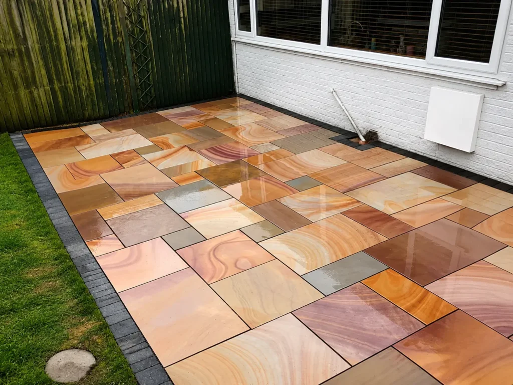 Newly finished Indian sandstone patio with dark block edging beside a home in Oxford